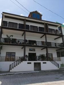 Un grand bâtiment blanc avec des balcons et des escaliers est à votre disposition. dans l'établissement La Posada De Don Jose, à Flores