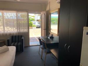 a room with a table and a chair and a door at Hervey Bay Motel in Hervey Bay