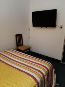 a bedroom with a bed and a flat screen tv on the wall at Departamento Plaza in San Salvador de Jujuy