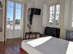 a bedroom with a bed and a chair and windows at Casa Londres in Estoril