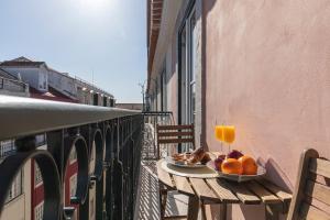a table with a plate of fruit and a glass of orange juice at Ando Living - São Nicolau Townhouse in Lisbon