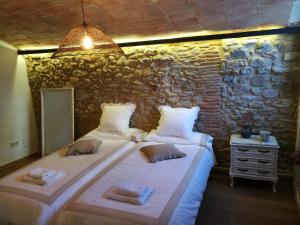 duas camas num quarto com uma parede de pedra em Can Puig de la Pera em La Pera