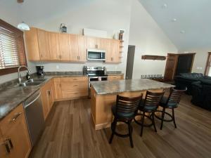 uma cozinha com armários de madeira e uma ilha de cozinha com cadeiras de bar em Overlook em Valemount