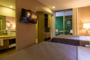 a hotel room with two beds and a bathroom with a television at Hotel Glow Point - Mulza in León