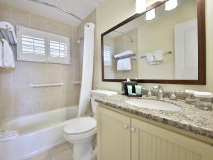 a bathroom with a toilet, sink, and mirror at Seaside Inn in Sanibel