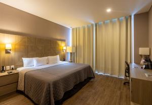 Habitación de hotel con cama y ventana en Hotel Glow Point - Mulza, en León