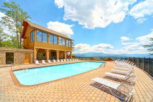 a swimming pool with lounge chairs and a building at Moondancer in Pigeon Forge
