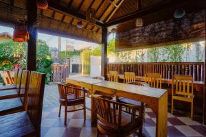 un restaurante con una gran mesa de madera y sillas en Taman Bali Homestay, en Sanur