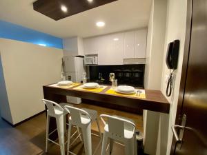 uma cozinha com um balcão com cadeiras e um frigorífico em Departamento Elegante y Relax by Torre Vento em Santa Cruz de la Sierra