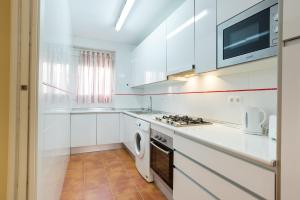 Biała kuchnia z kuchenką i kuchenką mikrofalową w obiekcie Alferez II by ELE Apartments w Maladze
