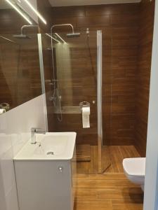 La salle de bains est pourvue d'un lavabo blanc et d'une douche. dans l'établissement Apartament w zieleni do wynajęcia blisko jeziora, à Środa Wielkopolska