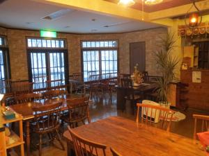 a restaurant with wooden tables and chairs and windows at Pension Marionette in Hakuba