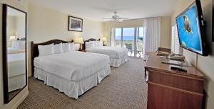 a hotel room with two beds and a television at Seaside Inn in Sanibel