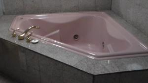 Laurel Inn في آوكلاند: حوض استحمام وردي مع صنبور في الحمام