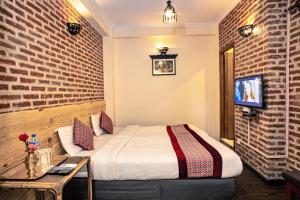 um quarto de hotel com uma cama e uma TV em Newa Home em Catmandu
