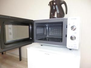 a microwave oven sitting on top of a white table at THE MICKEY CARLTON Ohashi 206 in Shiobaru
