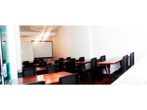 une salle de conférence avec des tables et des chaises et un écran de projection dans l'établissement Hotel Glorioso, à Oruro