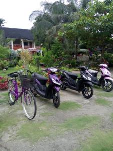 três scooters e uma bicicleta estacionada num quintal em SUNSHINE PARADISE Inn em Ilha de Bantayan