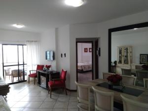 sala de estar con mesa, sillas y espejo en Apartamento Dante Tomio, en Balneário Camboriú