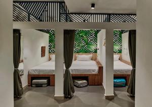 Un dormitorio con 2 camas y una pared con plantas. en Minimalist Poshtel & Suites en Nueva Delhi