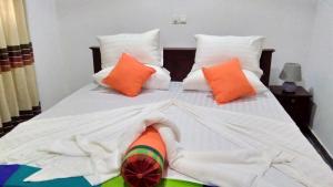 a large bed with orange and white pillows at Santosa Villa in Galle