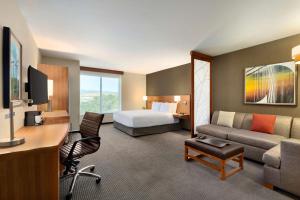 a large hotel room with a bed and a couch at Hyatt Place Vacaville in Vacaville