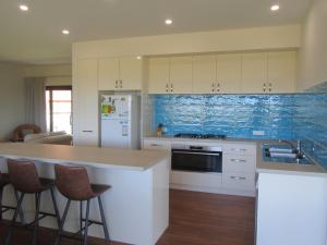 a kitchen with white cabinets and a counter with bar stools at Storm Bay Cottage in Augusta