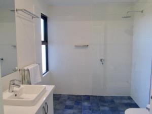 a white bathroom with a sink and a shower at Storm Bay Cottage in Augusta