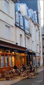 eine Gruppe von Tischen und Stühlen vor einem Gebäude in der Unterkunft Charmant duplex 2 pièces hypercentre de Granville in Granville