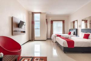 a hotel room with two beds and a red chair at RedDoorz Syariah @ Soekarno Hatta Indah 2 in Blimbing