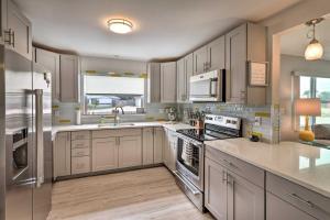 a kitchen with white cabinets and stainless steel appliances at Bright Bungalow with Porch Walk to Ormond Beach! in Ormond Beach