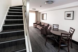 St Ives Apartments في هوبارت: غرفة بها درج وطاولة وكراسي