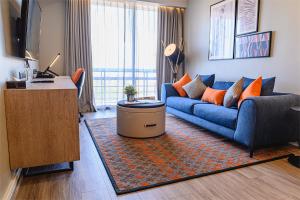 a living room with a blue couch and a large window at Oakwood Residence Sukhumvit Thonglor Bangkok in Bangkok