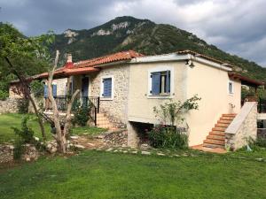 a small white house with a mountain in the background at Kalavrita Stone Villa in Planitéron