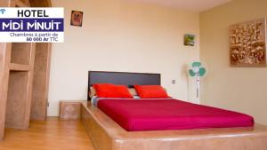 ein Schlafzimmer mit einem großen Bett mit roten Kissen in der Unterkunft Midi Minuit in Antananarivo
