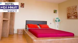 a bedroom with a large bed with red pillows at Midi Minuit in Antananarivo