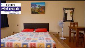 a bedroom with a bed and a table with a fan at Midi Minuit in Antananarivo +4 photos