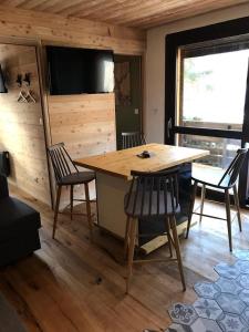 ラ・サル・レ・ザルプにあるAmbiance petit chaletの木製のテーブルと椅子、テレビが備わる客室です。