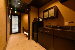 La cuisine est équipée d'un réfrigérateur noir et d'un évier. dans l'établissement Rinn Premium Machiya Yae, à Kyoto