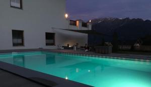 una piscina por la noche con una montaña en Apart Alpenstern, en Fiss