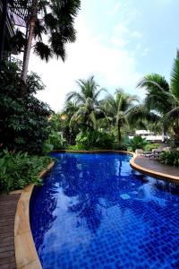 a blue swimming pool with palm trees in the background at Kata gardens 2 bedroom near Kata beach 3B in Kata Beach
