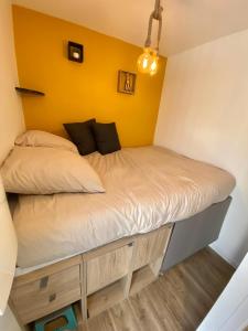 Cama en habitación con pared amarilla en La Petite Maison De Bord De Mer, en Guidel