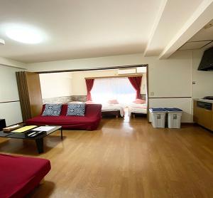 ein Wohnzimmer mit einem roten Sofa und einem Bett in der Unterkunft Laforet Tokaichi / Vacation STAY 75082 in Hiroshima