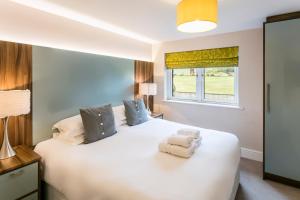 a bedroom with a large white bed with towels on it at Golf Apartment @ Carus Green in Kendal