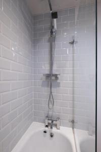 a shower in a white bathroom with a tub at 1 Roseanna Cottage, Middleton - Aldeburgh Coastal Cottages in Middleton