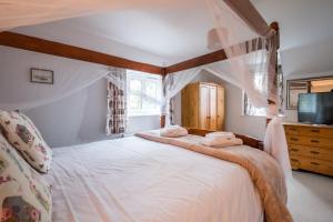um quarto com uma cama de dossel com lençóis brancos em 1 Roseanna Cottage, Middleton em Middleton
