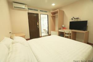 a bedroom with a bed and a desk and a television at Favori Hostel Bangkok Surawong in Bangkok