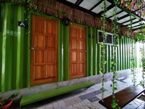 a green building with two doors and a table at THE BOXS CONTAINER HOMESTAY in Kuching