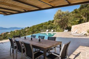 a wooden table and chairs on a patio with a pool at Villa Koumaria in Sivota