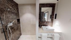 ein Bad mit einem Waschbecken und einer Dusche in der Unterkunft White Pearl Apartment 0.09 in Timmendorfer Strand
